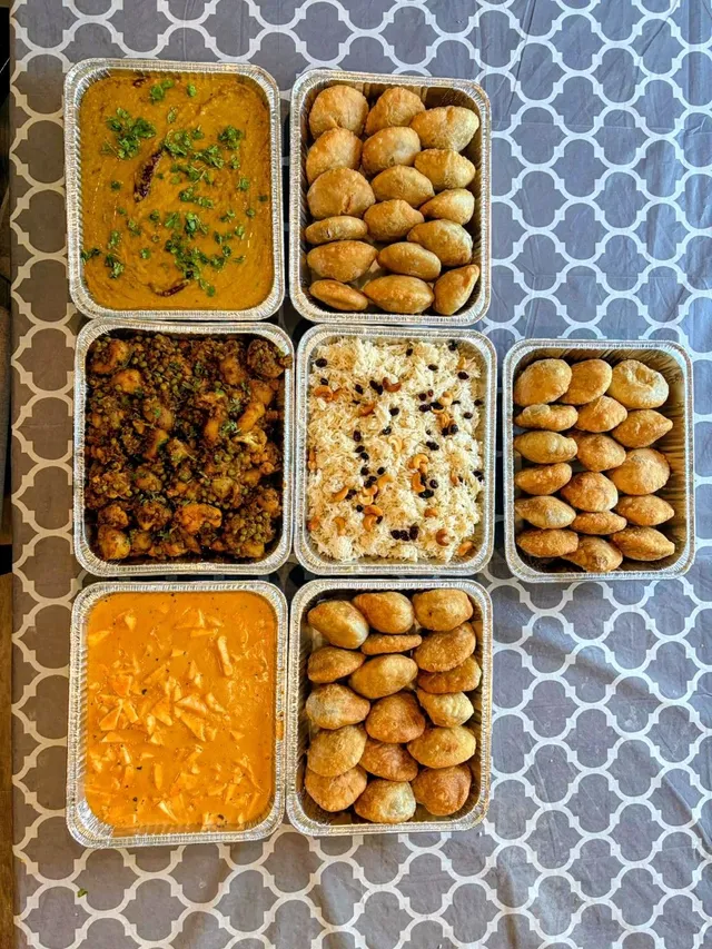 A full catering order of curries, rice and kachoris in trays